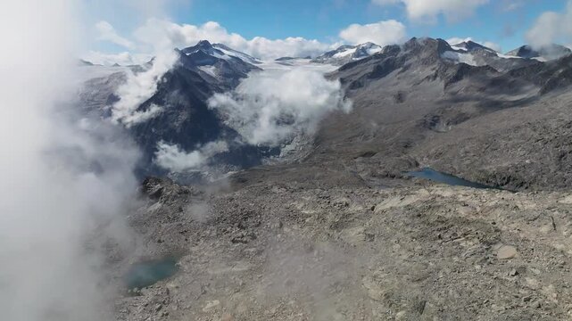 Aerial view of rugged mountains, interspersed with glacial ice and serene lakes, under scattered clouds, creating a striking contrast, Brescia, BS, Italia.