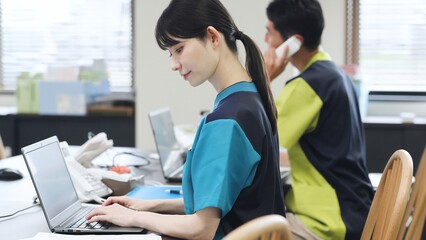 Obraz premium 事務仕事をするアジア人介護士