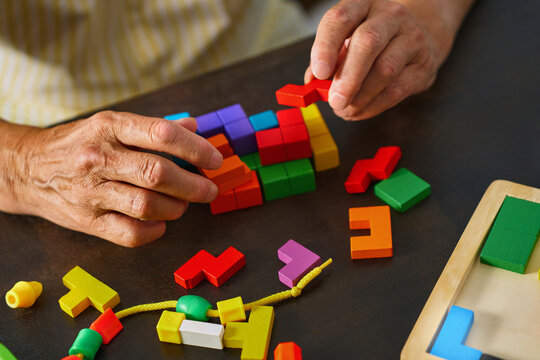 Elderly hand solving colorful puzzle for mental health exercise