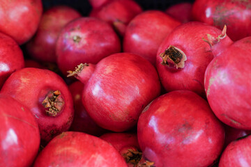 fresh red pomegranates piled together, highlighting their vibrant color and texture