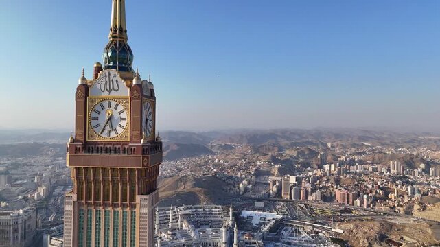 drone footage of Mecca, Saudi Arabia, filmed at sunset. The video captures the vast urban landscape with residential buildings, modern towers, and surrounding mountains bathed in golden hour light