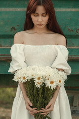 a young girl in a beautiful beige dress with flowers near the cart. film and grain effect