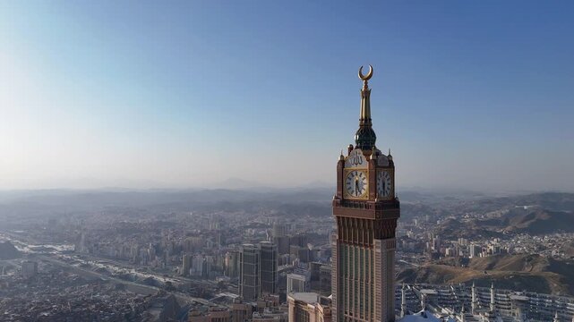 drone footage of Mecca, Saudi Arabia, filmed at sunset. The video captures the vast urban landscape with residential buildings, modern towers, and surrounding mountains bathed in golden hour light