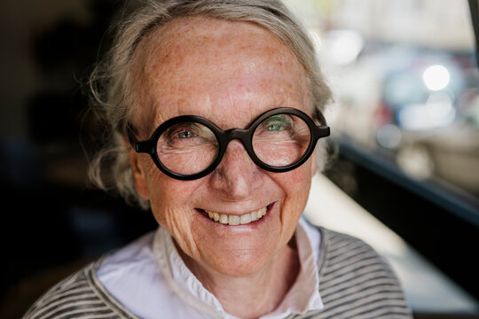 Confident smiling woman with glasses in cafe showing self assurance