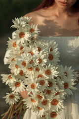 a bouquet of white daisies in close-up in the hands of a girl. film and grain effect