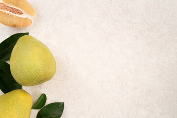 Fresh pomelo fruit with leaf on white table background.