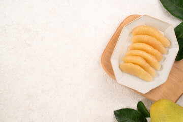 Fresh pomelo fruit with leaf on white table background.