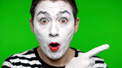 Mime Points With Shocked Expression on Green Screen Background, Emphasizing White Face Paint and Black Striped Shirt