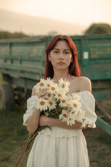 Close up portrait of young woman with bouquet of daisies outdoors