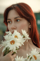 Close up portrait of young woman with bouquet of daisies outdoors