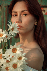 Close up portrait of young woman with bouquet of daisies outdoors