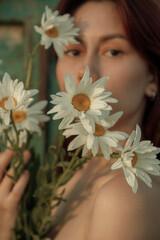 Close up portrait of young woman with bouquet of daisies outdoors