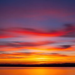 Fototapeta premium Vibrant sunset hues paint the tranquil sky above a still lake, reflecting the fiery colors onto the water's surface.