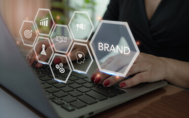 Close-up of hands typing on a laptop with holographic hexagon icons representing branding, marketing, growth, and business strategy. The central hologram highlights the word &ldquo;BRAND&rdquo; as the focus.