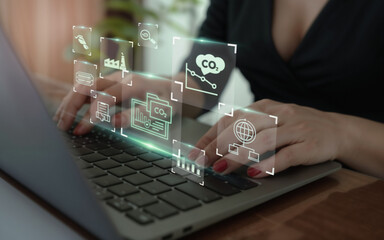 Hands typing on a laptop with holographic icons of CO2 emissions, climate data, and sustainability analytics. Concept of digital tools for carbon footprint monitoring, green technology, and eco report