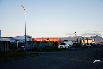 Industrial street scene in Akranes Iceland with warehouses and distant mountains at sunset