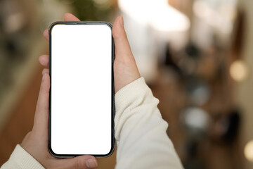 Mockup of a hand holding mobile phone with blank white screen in cafe