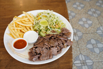 Kebab - grilled meat with french fries and vegetables on wooden background