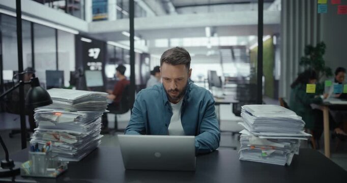 Tired Man Overwhelmed with Work Sitting and Working on a Laptop Computer. Tasks Keep Piling Up and Adding to His Stress Level. Male Managers Closes the Laptop and Leaves - Powered by Adobe