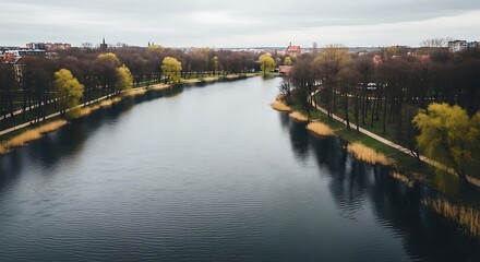 Obraz premium Aerial view of a serene river flowing through a vibrant autumn landscape with lush trees and a clear sky.