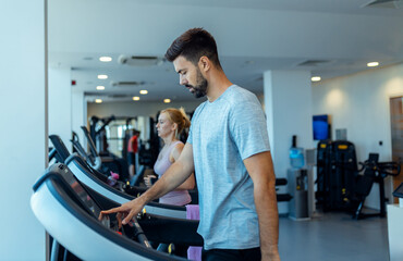 Man preparing to run setting up treadmill at gym.