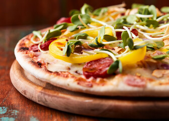 Pizza with chorizo ​​sausage, mozzarella cheese and yellow pepper. Rustic wooden background. Soft focus.	