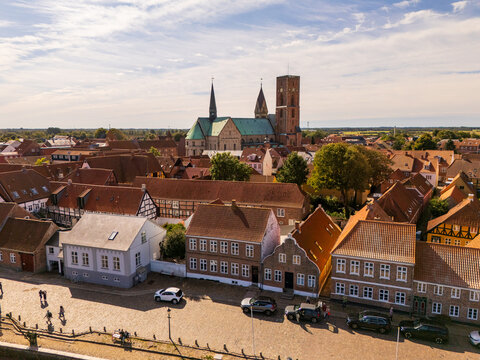 Aerial view of the imposing Ribe Cathedral standing tall amidst the charming red-roofed buildings, blending history with the vibrant life of the town, Ribe, Denmark.