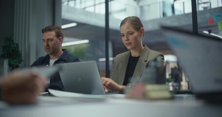 Portrait with a Female Seated Together with Office Workers Behind a Large Table, Each Working on Laptop Computers During a Team Session. Colleagues Exchange Quick Notes while Concentrating on Tasks - Powered by Adobe