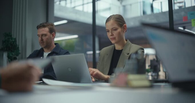 Portrait with a Female Seated Together with Office Workers Behind a Large Table, Each Working on Laptop Computers During a Team Session. Colleagues Exchange Quick Notes while Concentrating on Tasks
