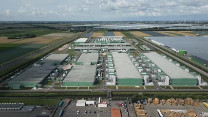 Drone footage of a large data center complex at Agriport Eemshaven, surrounded by farmland and sustainable energy facilities in the Netherlands. - Powered by Adobe
