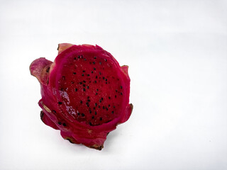 A close-up of a half dragon fruit shows the vibrant pink flesh with small black seeds. Isolated against a white background, it showcases the fruit's texture and color
