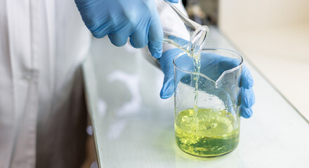 Scientist or medical in lab coat holding test tube with reagent, mixing reagents in glass flask in laboratory research.