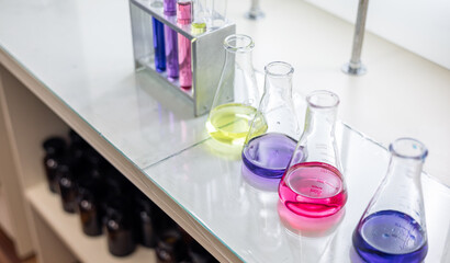 Laboratory analysis. Flask and test tubes on white table indoors, closeup. Laboratory test-tubes and retorts. Scientific equipment at laboratory.
