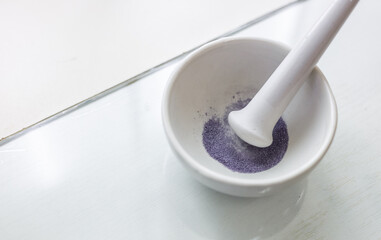 A chemist grinds reagents in a mortar. Preparing a reagent for laboratory testing.