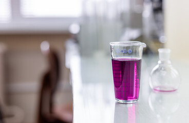Chemistry laboratory glassware with color liquids. Laboratory analysis. Glassware with different liquids on white table indoors, closeup.