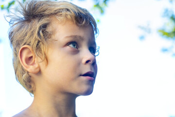 Portrait of a little boy with blond hair in nature