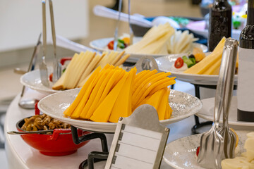 Food Still Life - Variety of Aged Cheeses Spread Out white Table in front of Black Background with Copy Space. Luxury hotel open buffet, wide variety of cheeses