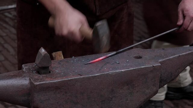 Blacksmith works on glowing metal with hammer and anvil in Rotterdam Netherlands