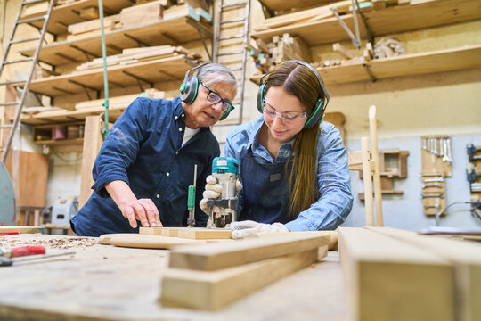 Young apprentice learning woodworking skills with experienced mentor