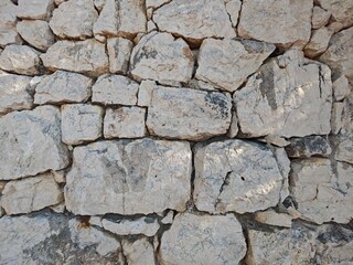 Rugged stone wall texture showcasing natural weathering and unique patterns in sunlight