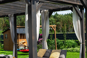 The terrace behind the house is made of beams, with visible curtains and decorative LED lights.