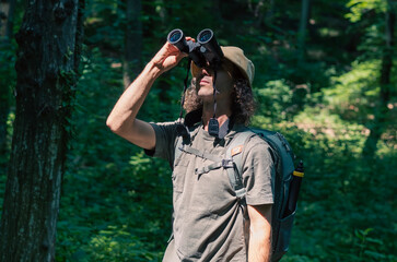 Traveler young man looking through binoculars outdoor, front view..Traveler young man looking through binoculars outdoor, front view..
