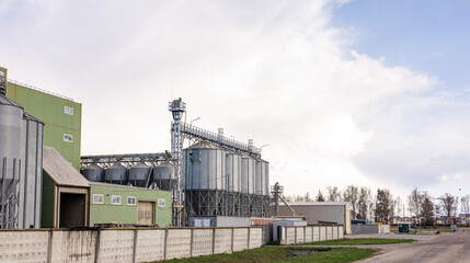 A low-angle view of large fly ash silos at an industrial plant, showcasing the towering infrastructure used for ash storage and processing. The silos are equipped with ladders and metal support struct