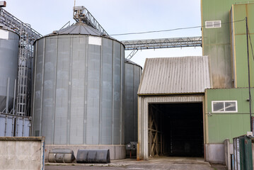 Plant for processing and silos for drying cleaning and storage of agricultural products, flour, cereals and grain. Silver tanks close-up. Silos in a barley field. Storage of the crop © NastyaPhoto