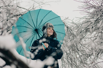Happy woman with a blue umbrella in the snow