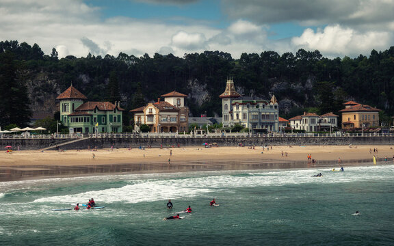 Surfers and Beachgoers in Front of Elegant European Coastal Town