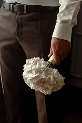 Wedding bouquet of white flowers in the hands of the groom