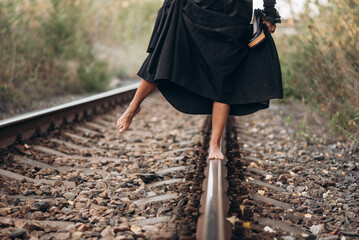 Barefoot Woman Balances on Railway Track in Black Dress