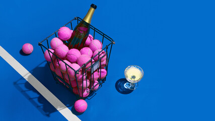 Pink tennis balls with champagne bottle and glass on blue court. Concept of sports lifestyle hedonism, cocktail branding, party promotion, and premium editorial content.