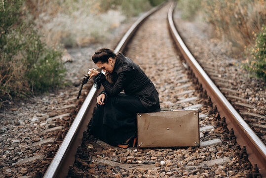 Woman Aiming Revolver in Vintage Attire Outdoors